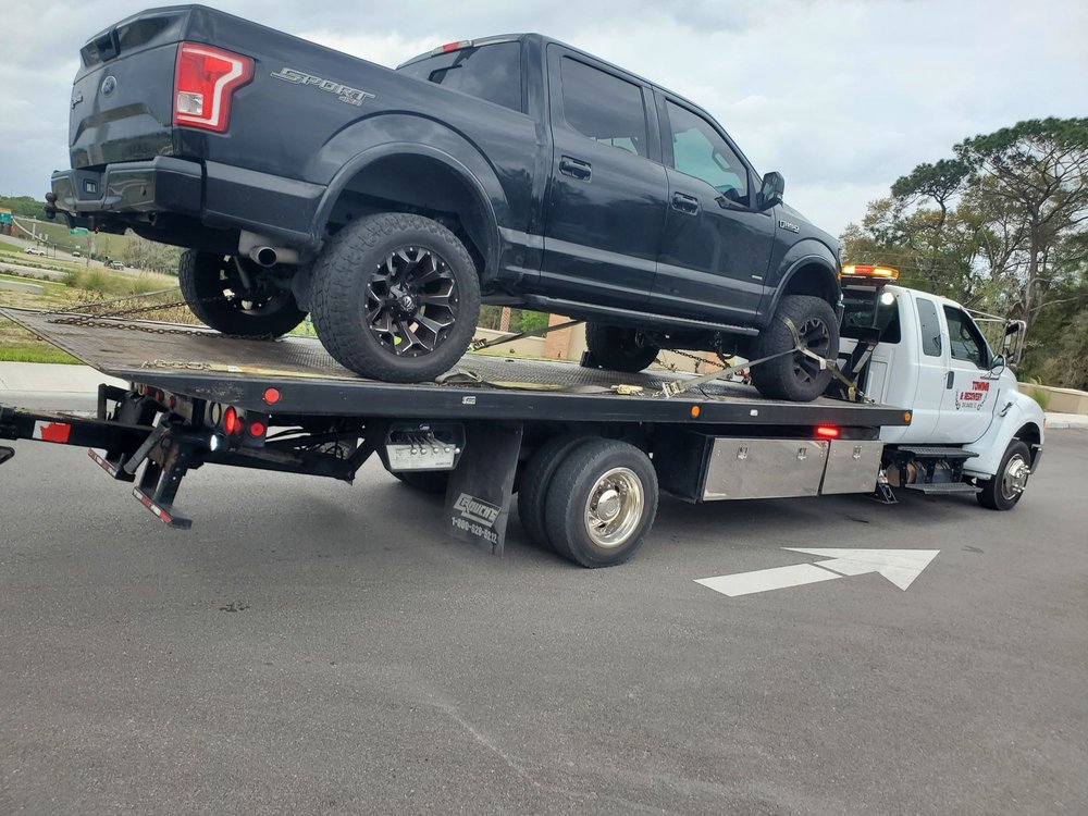 DLJ Towing flatbed truck carrying a black pickup in Orlando