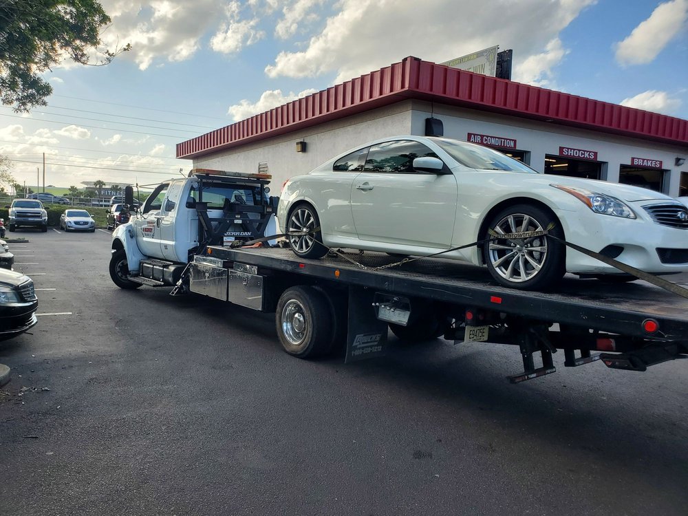 DLJ flatbed truck carrying a sedan after roadside assistance