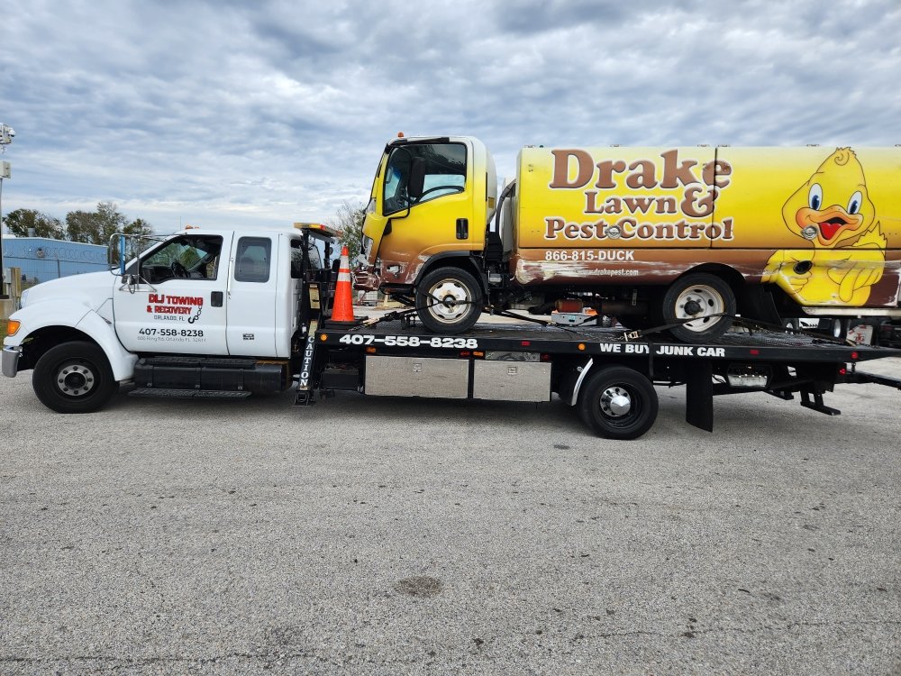 DLJ flatbed towing a commercial lawn-care truck in Orlando